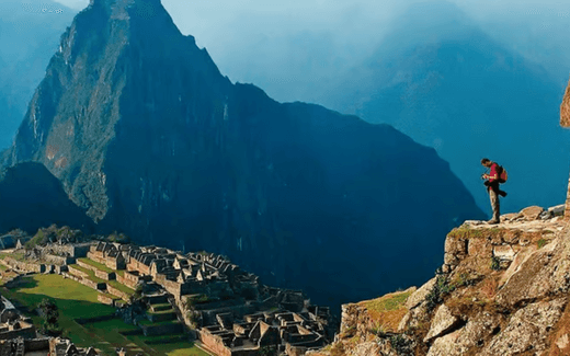 A hiker overlooking the breathtaking ruins of Machu Picchu and looming mountains in the background - 4-Day Inca Trail to Machu Picchu - Adventure Compass Blog By Global Trekker.